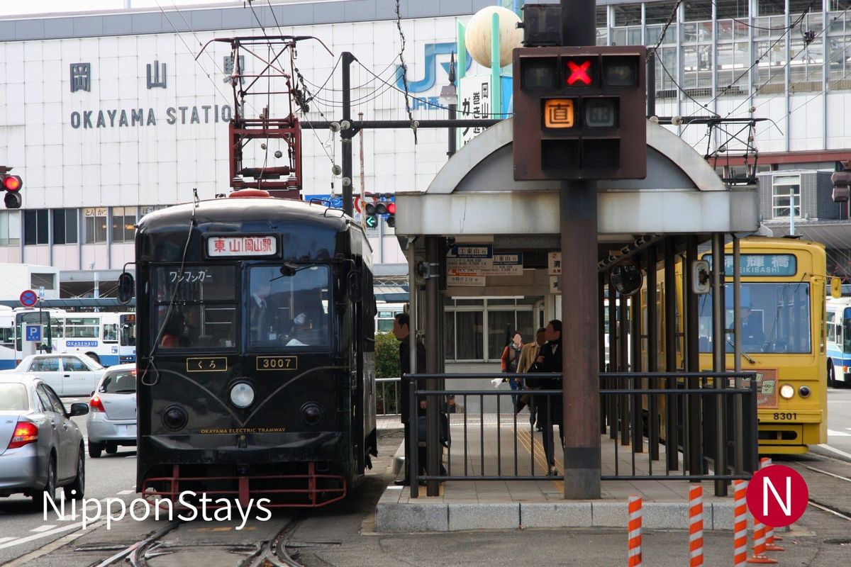 A tram waiting at the stop outside Okayama Station