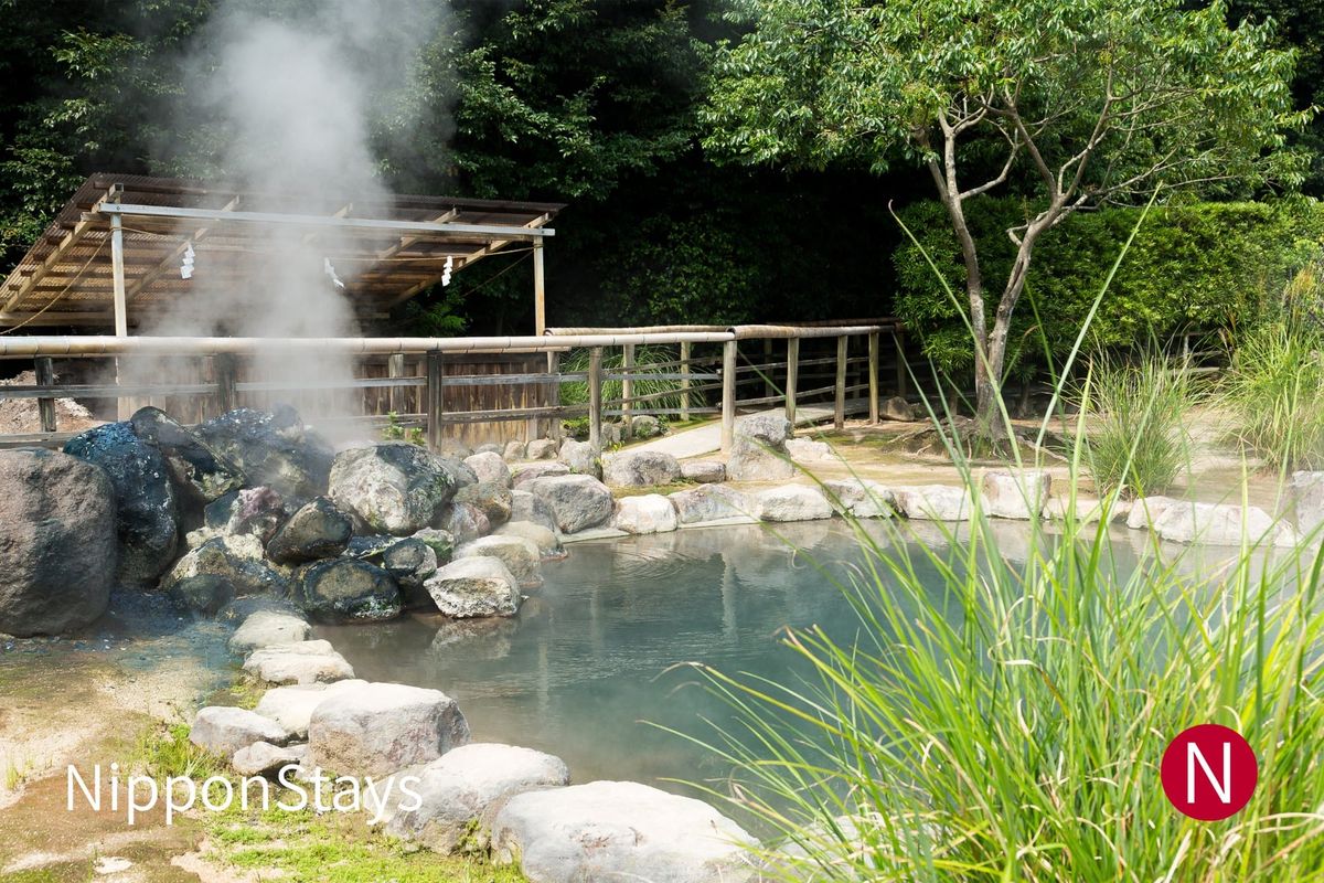 An open-air hot spring pool with steam rising off the water