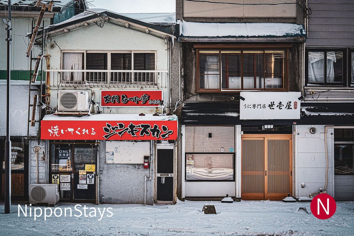A snow-covered street of small shopfronts in Hakodate