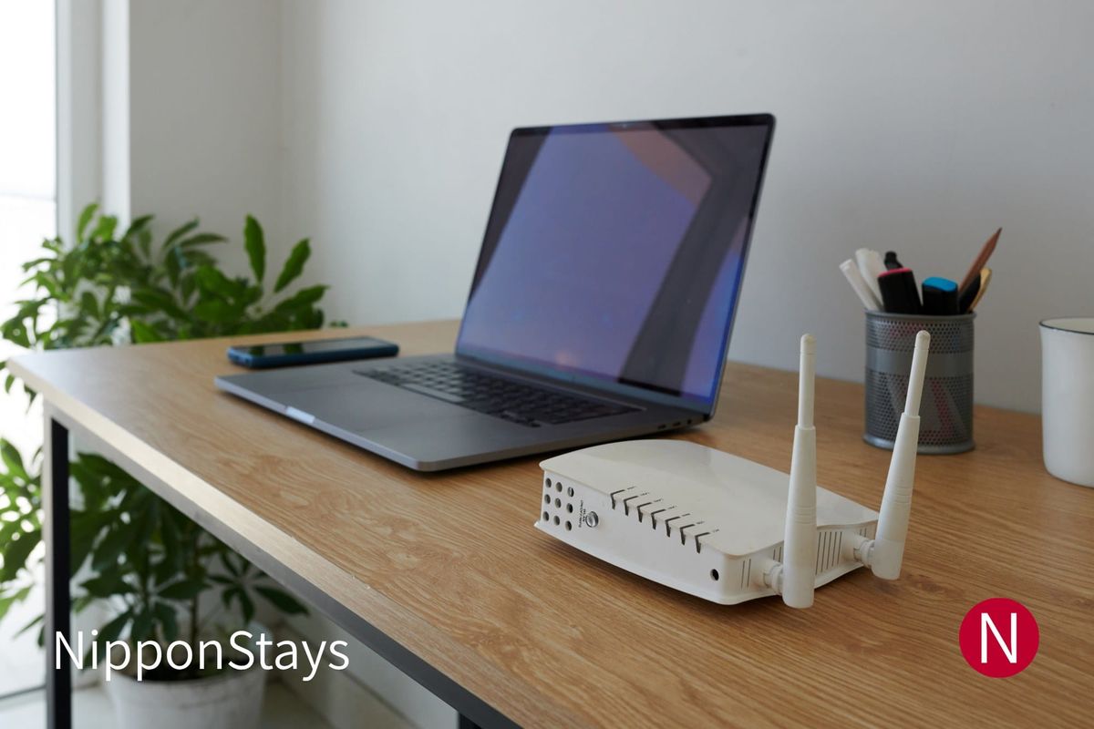 A Wi-Fi router beside a laptop on a desk