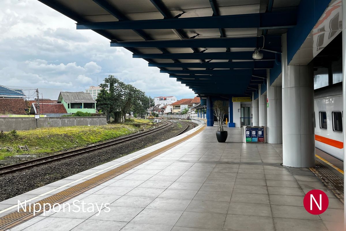An open station platform with a train waiting at the far end