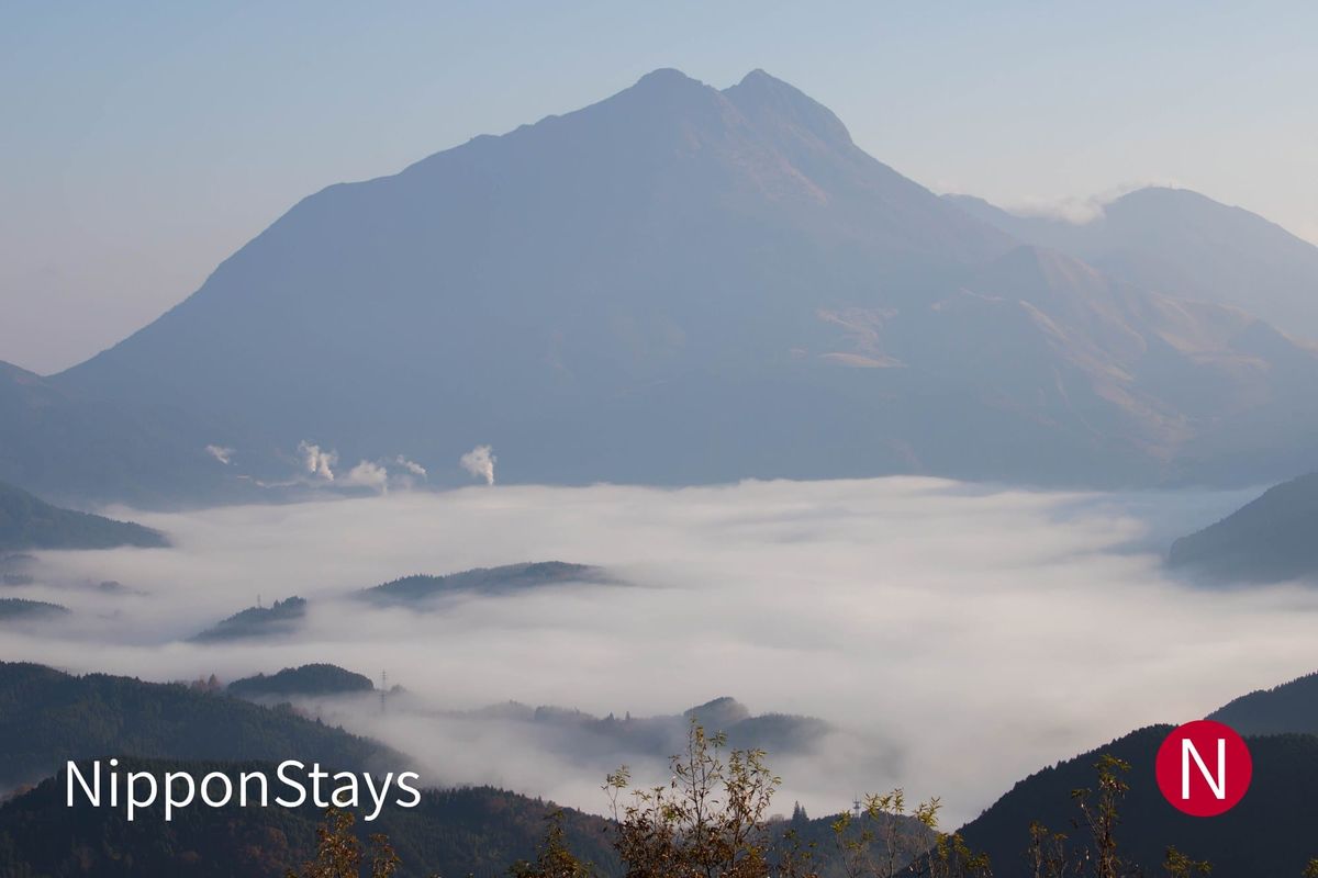 A twin-peaked mountain rising above a valley filled with morning cloud