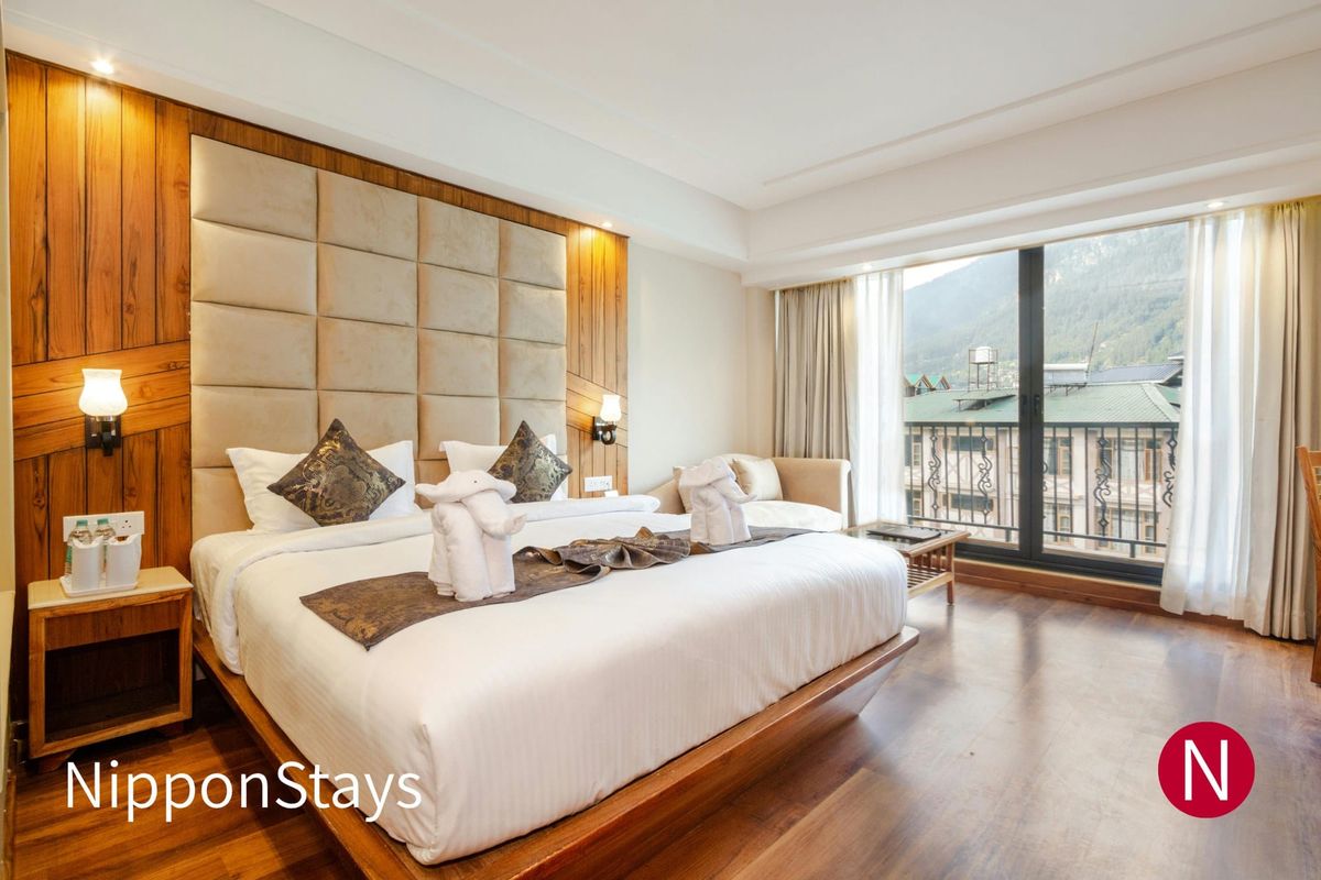 A compact modern hotel room with a large bed and wooden floor
