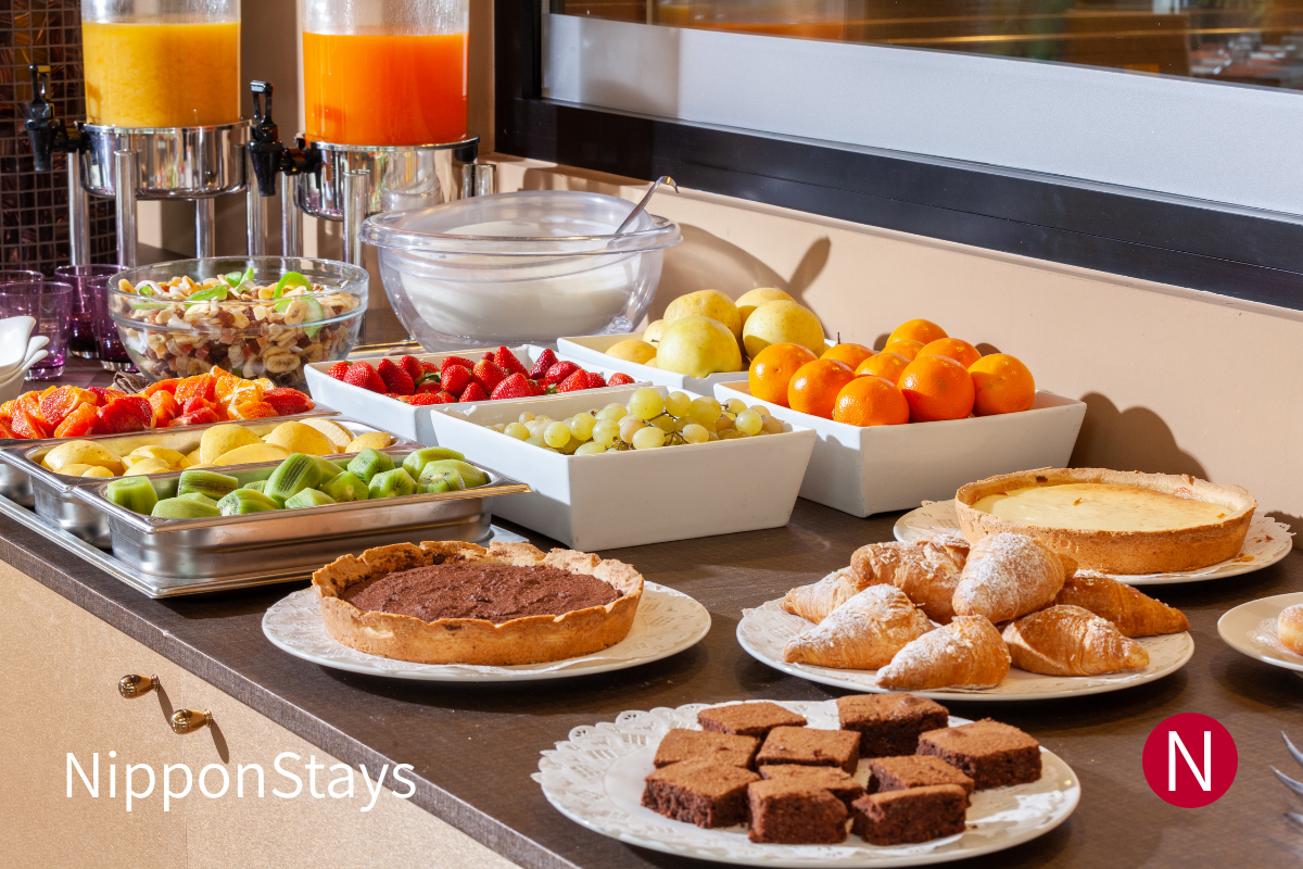 A hotel breakfast buffet with fruit, bread and drinks, with no guests visible.