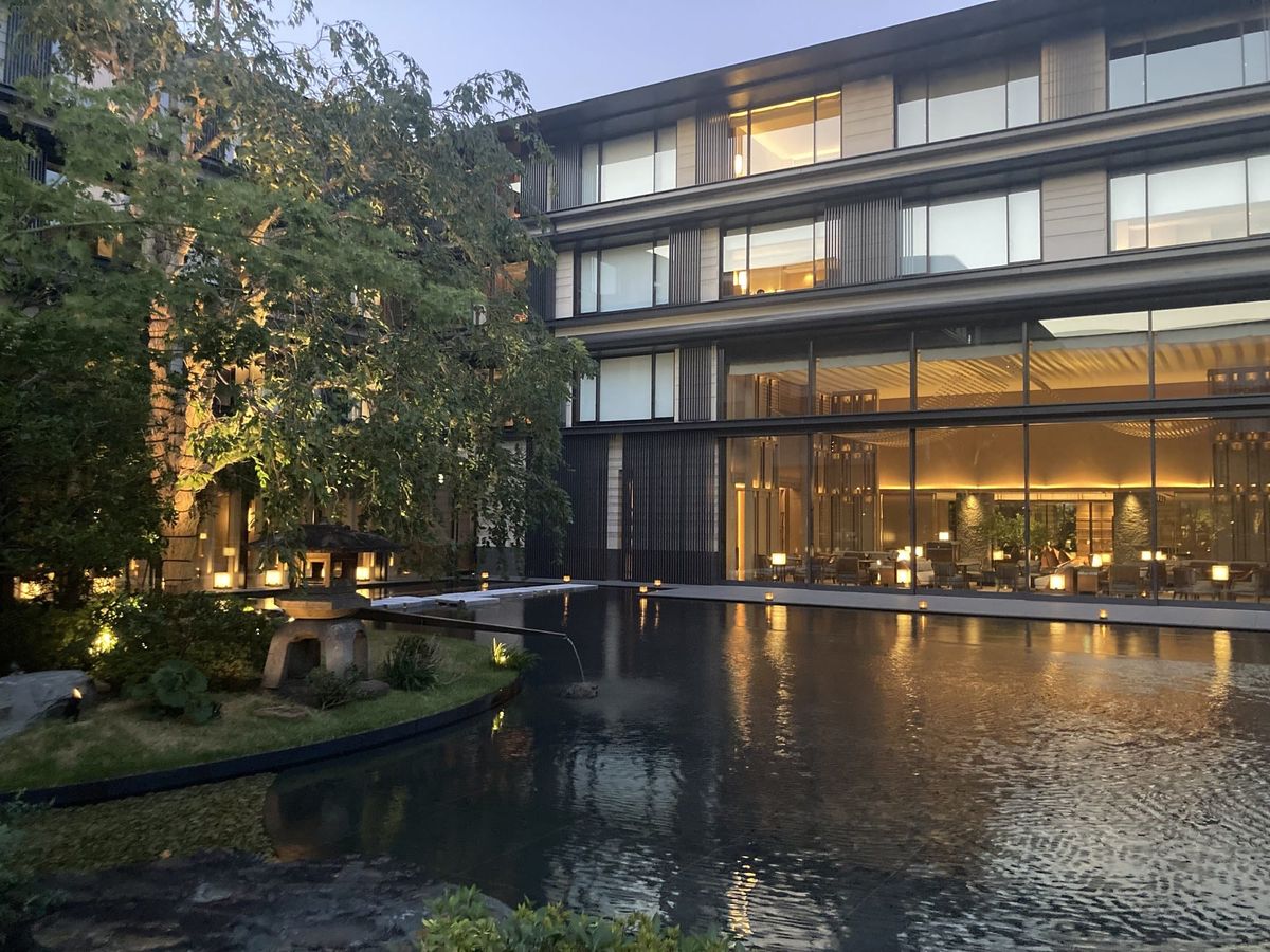 Evening view across a water basin toward a hotel garden lounge in Kyoto