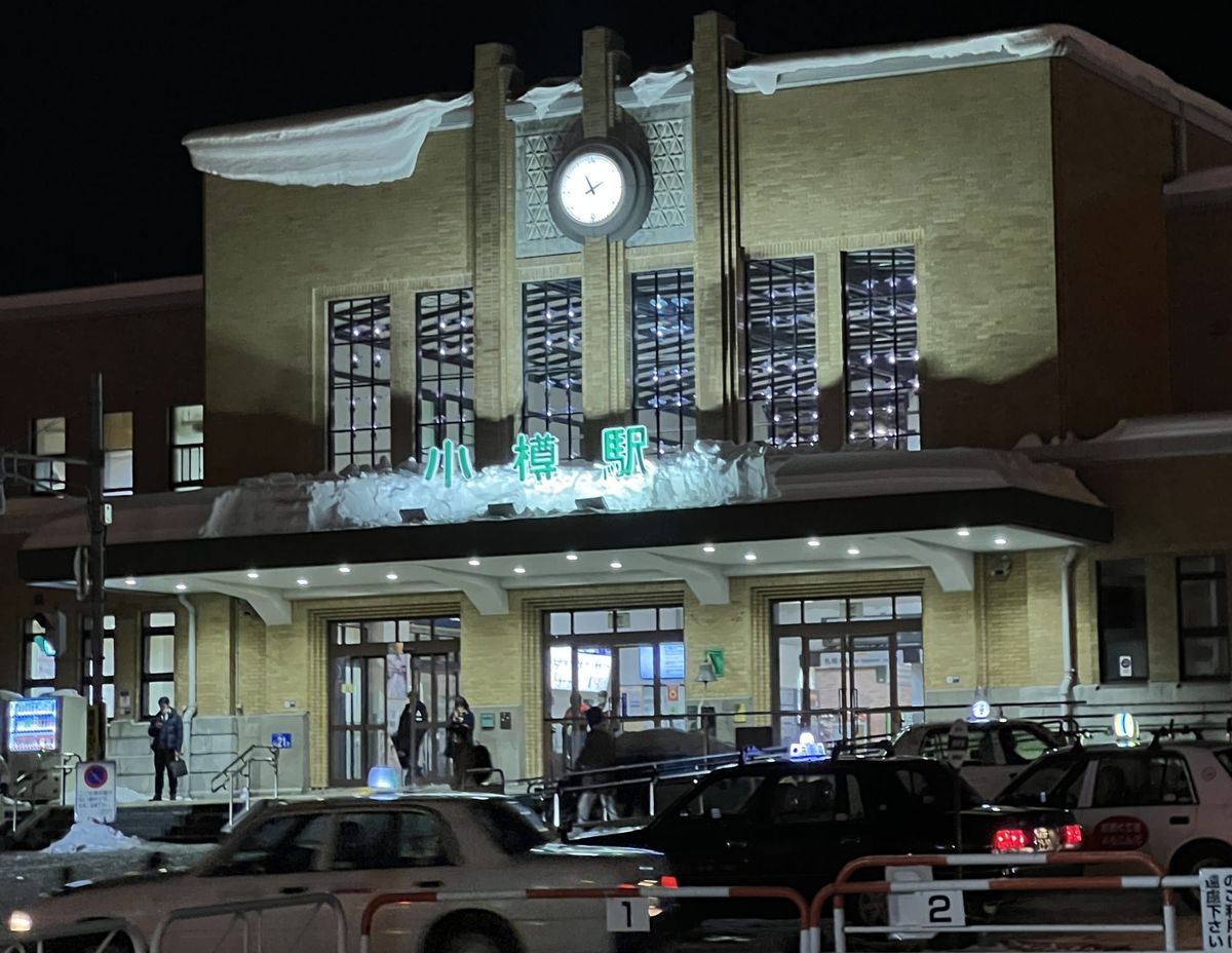 JR Otaru Station lit at night with snow on the roof and taxis waiting at the rank