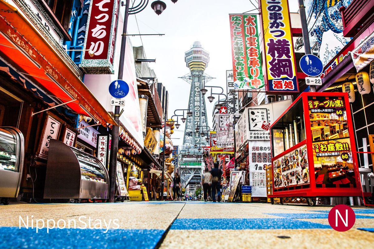 Tsutenkaku Tower at the end of a Shinsekai street lined with kushikatsu restaurant signs