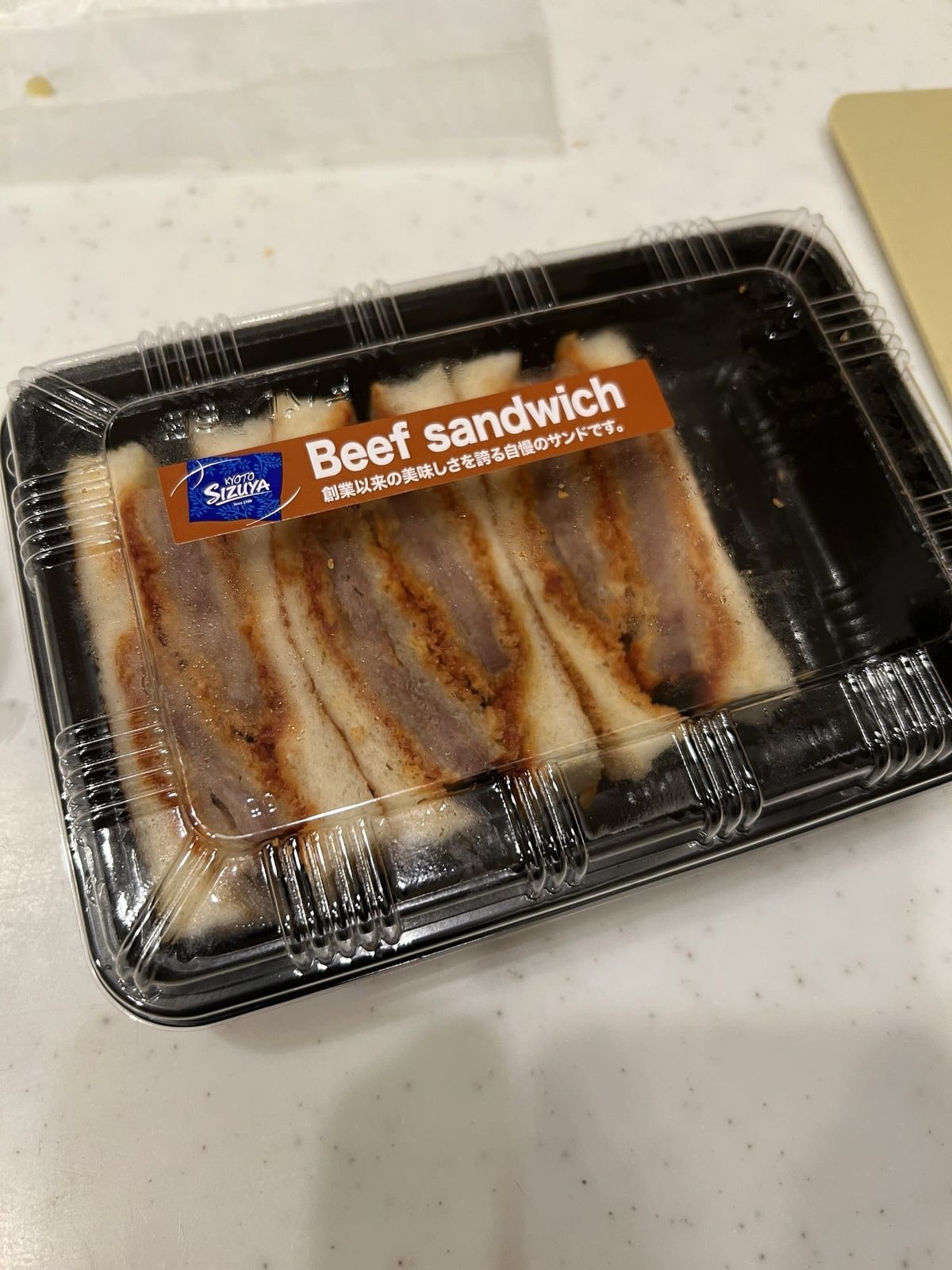 A Kyoto beef katsu sandwich in its takeaway pack, cut into thick slices