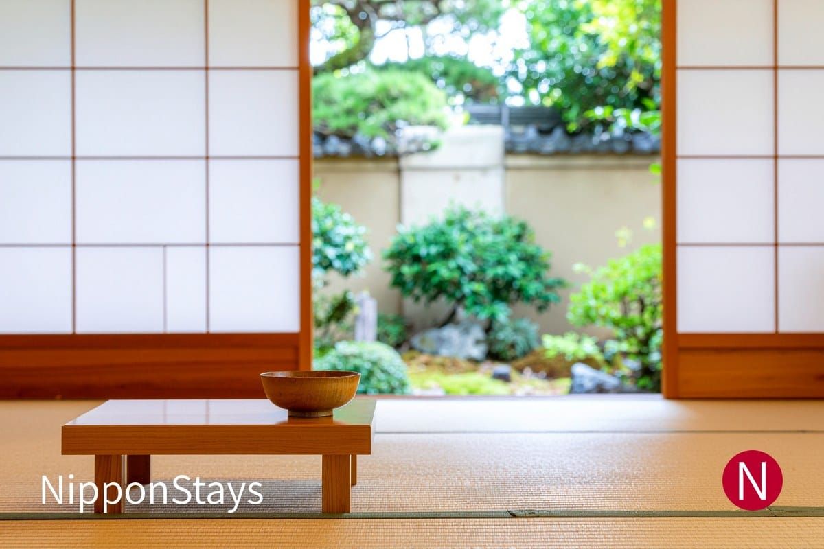 A tatami room in a Japanese inn with the shoji open onto a garden, no guests present