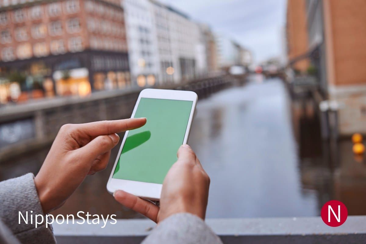 A hand holding a smartphone and typing a message on a city street