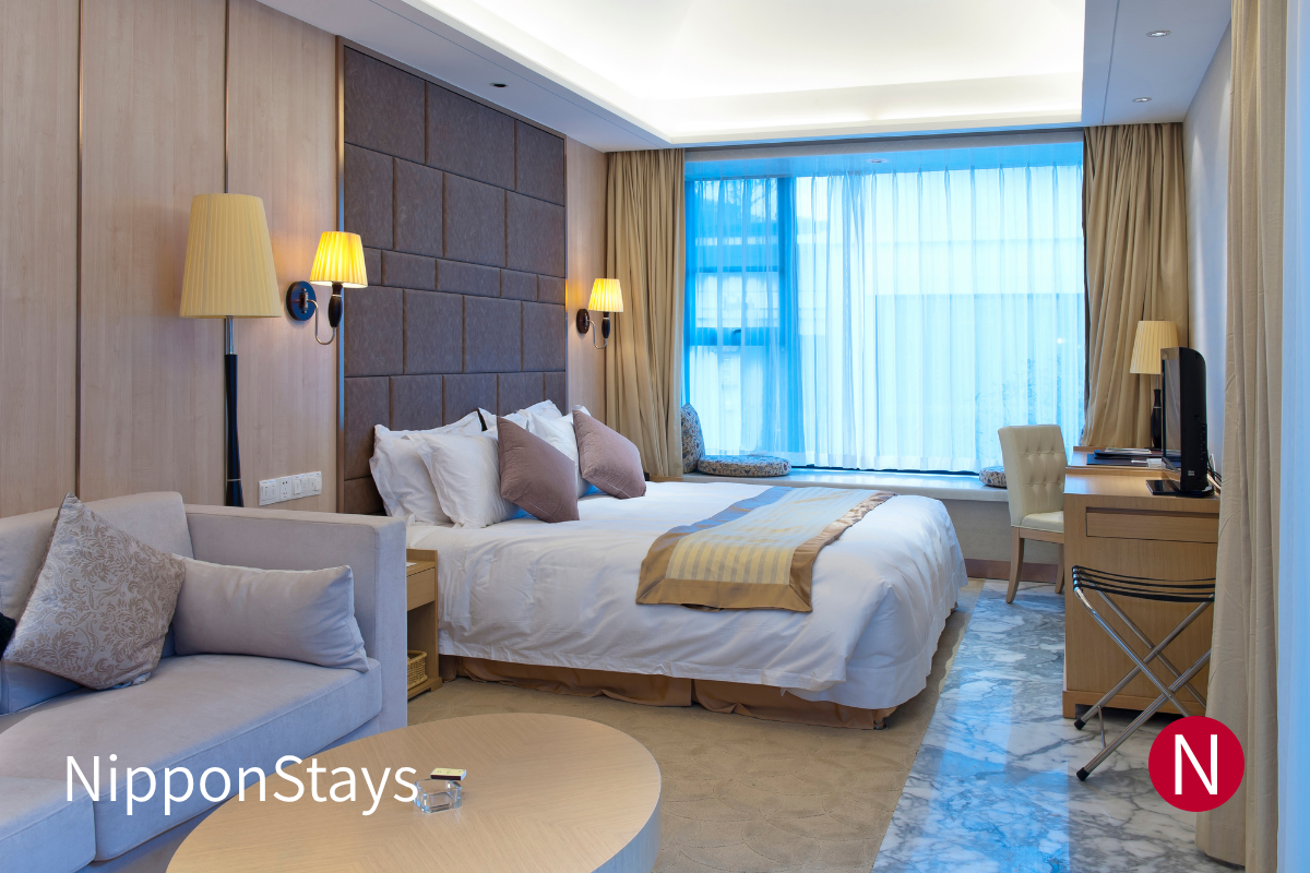 An empty hotel room in Tokyo with a bed, desk and window.