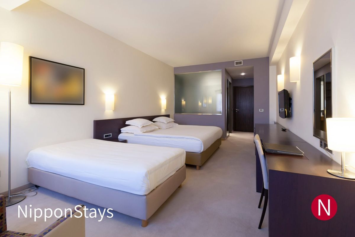 Two double beds side by side in a hotel room with a desk