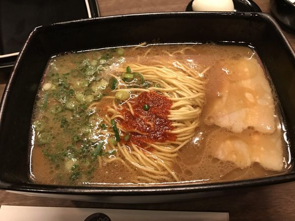 Bowl of Hakata tonkotsu ramen with thin noodles, green onions, and spicy paste