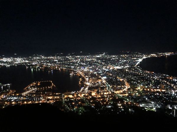 Panoramic night view of Hakodate from the Mt. Hakodate ropeway summit, city lights curving along the isthmus