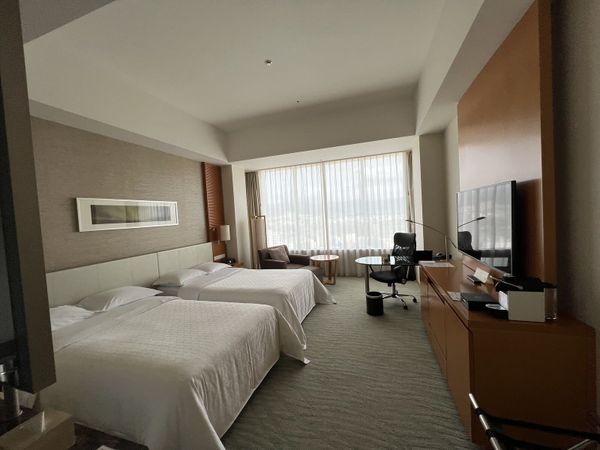 Twin hotel room in Hiroshima with large windows and a work desk