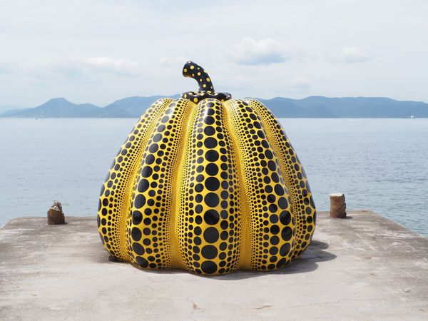 Yayoi Kusama's yellow pumpkin sculpture with black polka dots on a pier by the Seto Inland Sea