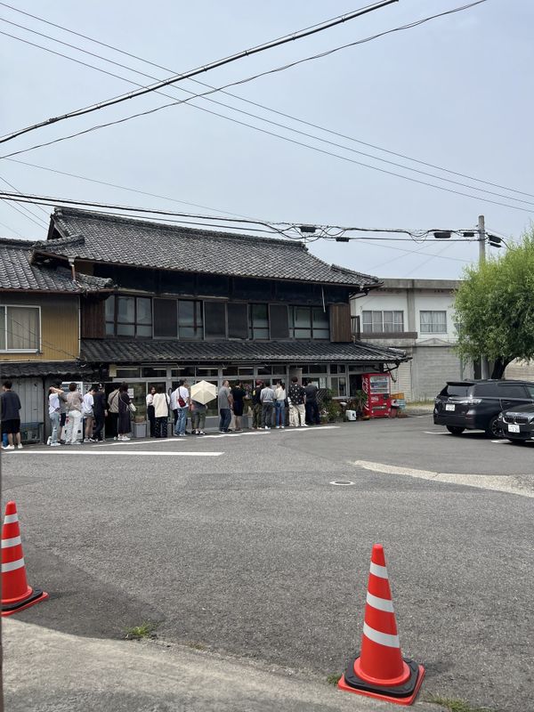 A line of customers waiting outside an old wooden udon shop in Takamatsu