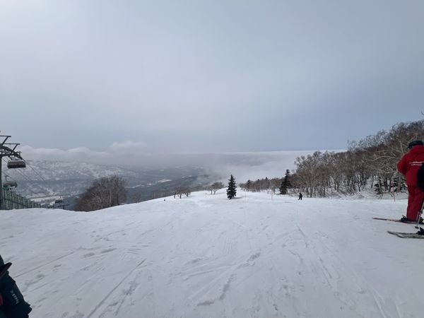 A Club Med staff member in the red uniform on a Kiroro piste overlooking the valley