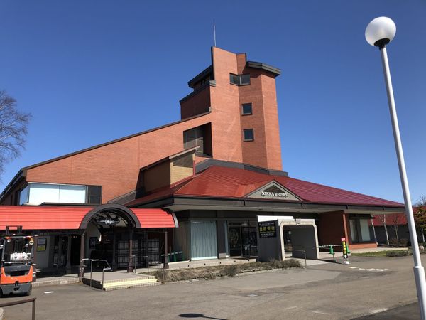 The red-roofed visitor reception building of the Nikka Whisky Yoichi Distillery under a blue sky