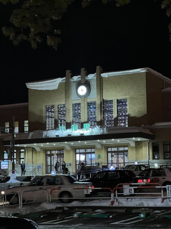Otaru Station illuminated at night in winter with snow-covered eaves and the station clock tower