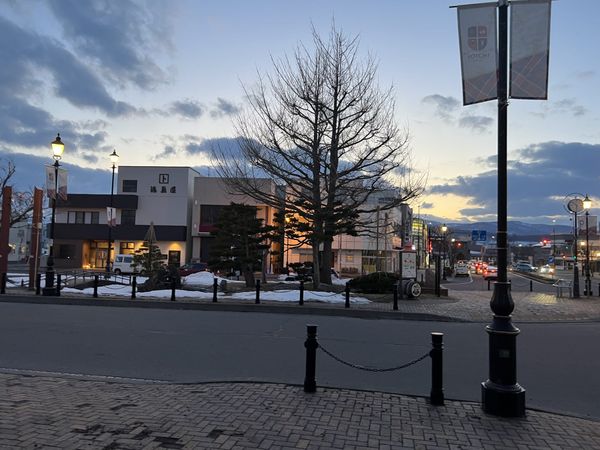 The street in front of JR Yoichi Station at dusk, with lampposts and banners