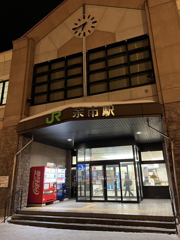 The entrance of JR Yoichi Station lit up at night with its station clock