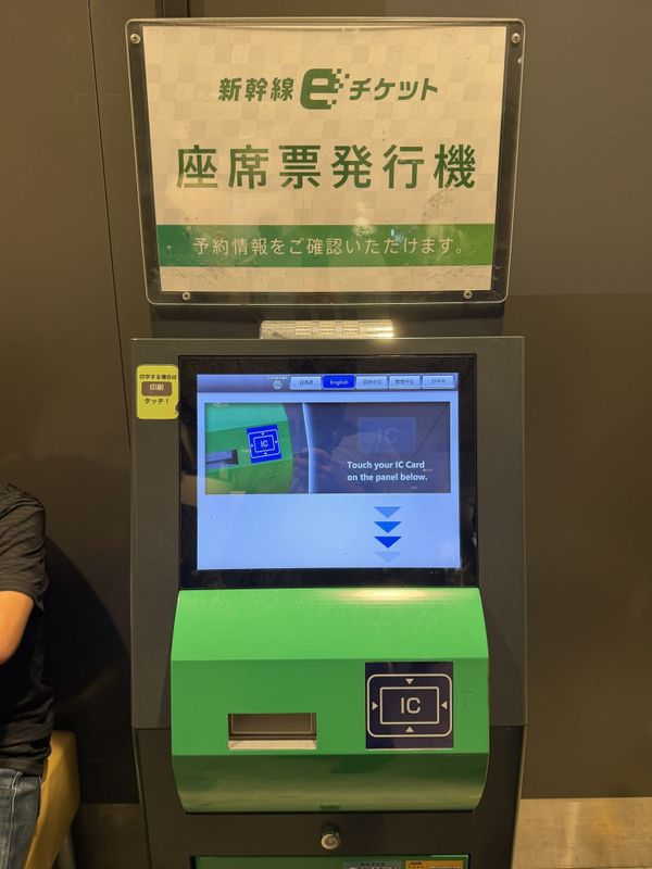 Seat-slip issuing machine at Tokyo Station's shinkansen gates, English option selected, prompting the traveller to touch an IC card on the panel