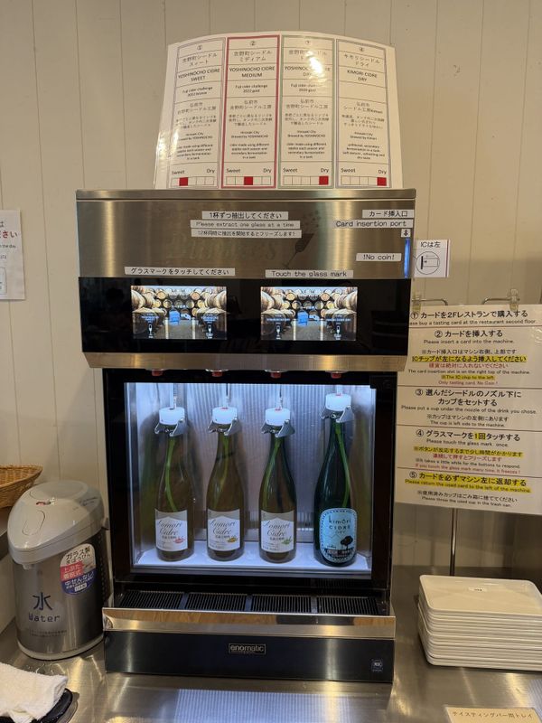 Self-serve cider tasting machine at A-FACTORY in Aomori, with the five operating steps printed in English beside it