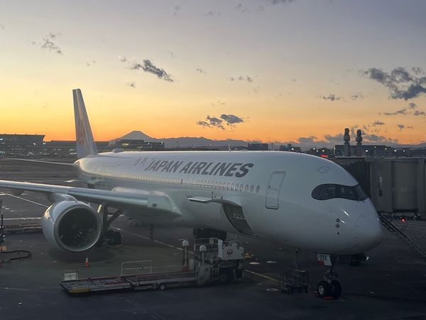 A JAL Airbus A350 at a Haneda gate at sunset with Mount Fuji on the horizon