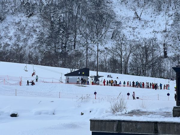 Queue of skiers and ski school groups at the Family Lift at the base of Kiroro