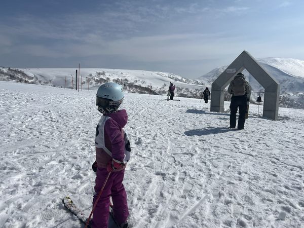 Child skier at the Kiroro summit photo frame under a blue sky with full snow cover
