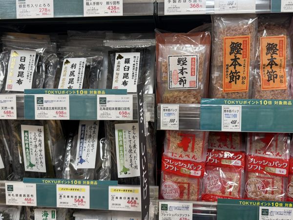 Packets of dried kombu and packets of dried bonito flakes displayed side by side on a Japanese supermarket shelf