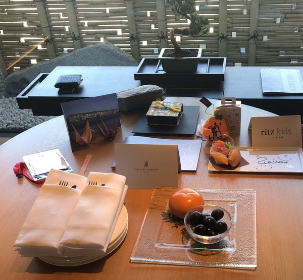 A welcome set-up on the table of a Ritz-Carlton Kyoto suite: a Ritz-Carlton Kyoto card, a ritz kids card, madeleines and jell