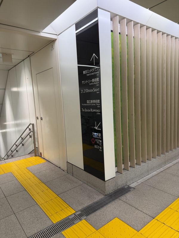 Underground wayfinding sign at Roppongi Station listing walking distances to Tokyo Midtown and nearby museums