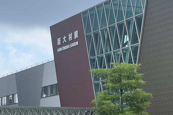 Shin-Omura Station on the Nishikyushu Shinkansen, a modern building with a diamond-patterned glass wall above dark red tile