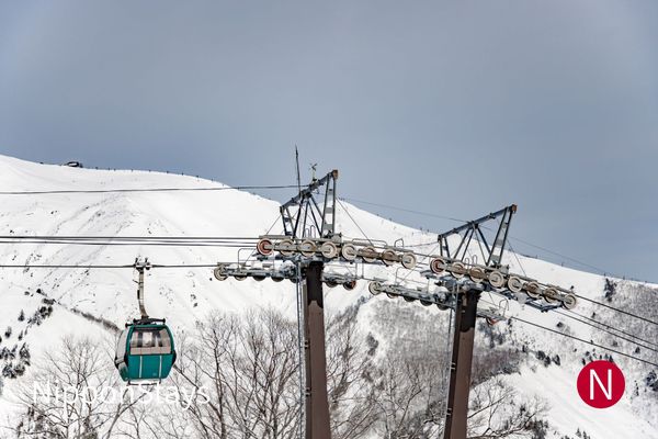 A gondola cabin climbing above a snow-covered ski area
