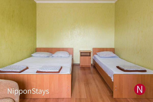 A plain budget hotel room with two single beds and a small side table