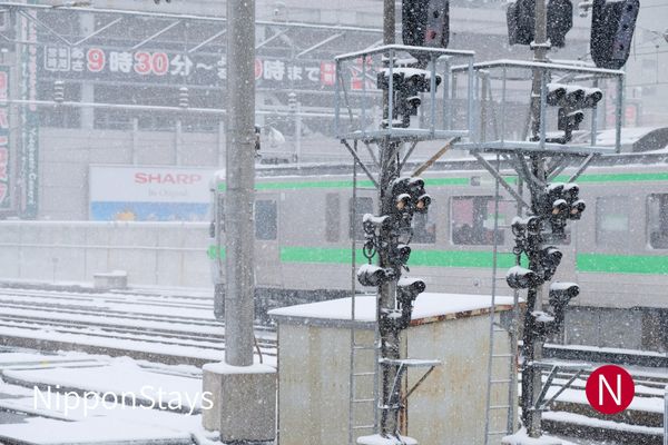 Snow falling over station tracks and overhead wires in Sapporo