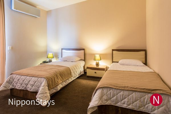A simple twin hotel room with two beds and bedside lamps