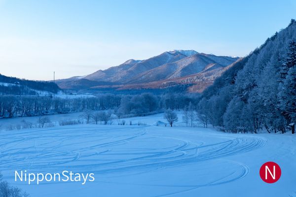 A wide snow-covered valley ringed by low mountains in Hokkaido