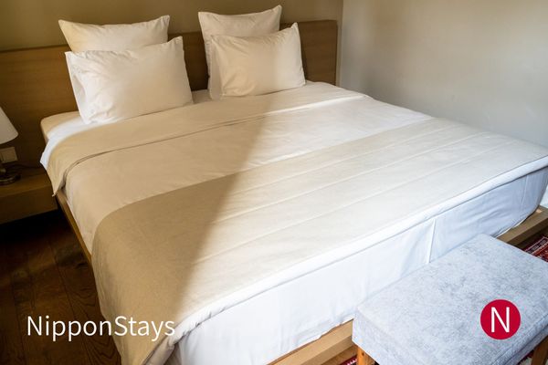 A small hotel room with a double bed and white linen