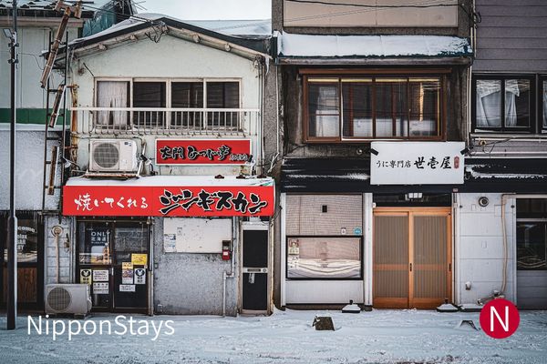 A snow-covered street of small shopfronts in Hakodate