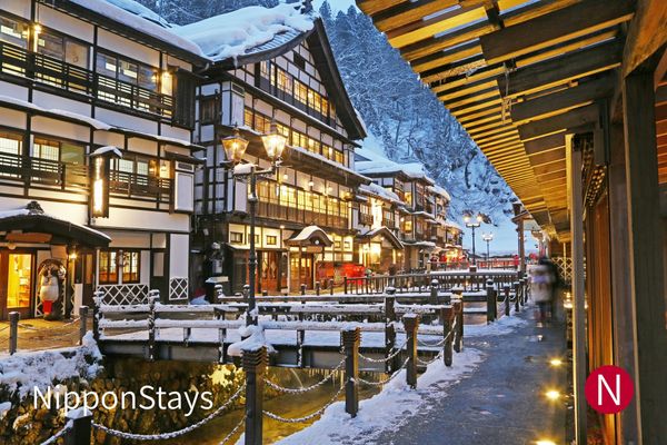 Wooden ryokan buildings lining a snow-covered river street at Ginzan Onsen