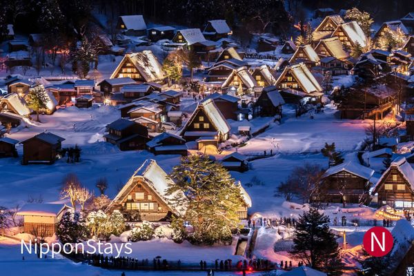 Gassho-style farmhouses lit up under snow at Shirakawa-go in the evening