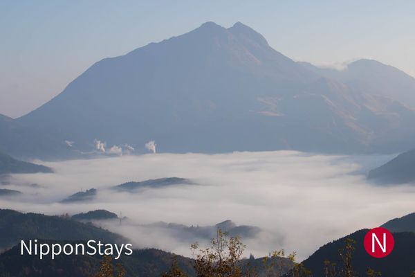 A twin-peaked mountain rising above a valley filled with morning cloud