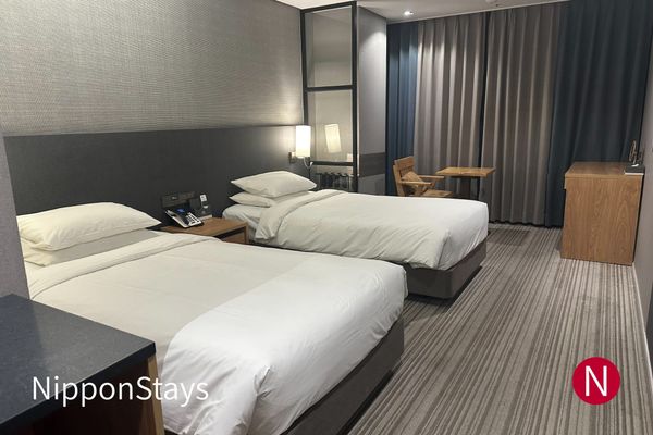A modern hotel room with two beds and a window