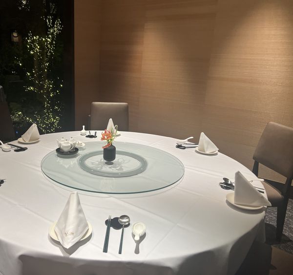 A round table set with a turntable at Star Hill, The Capitol Hotel Tokyu, with the lit garden visible through the window