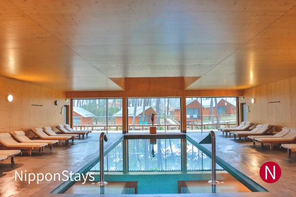 An empty indoor hotel pool with loungers along one side