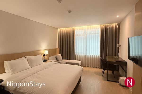 An empty modern hotel room in Japan with a bed, desk and window.