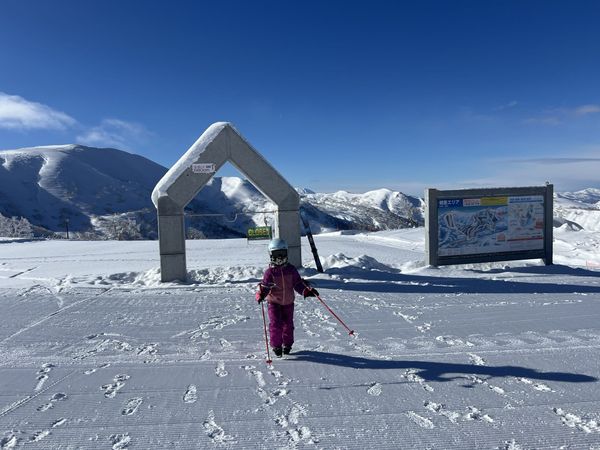 The summit arch at Kiroro ski resort in Hokkaido, with a snow-depth marker and a trail map board